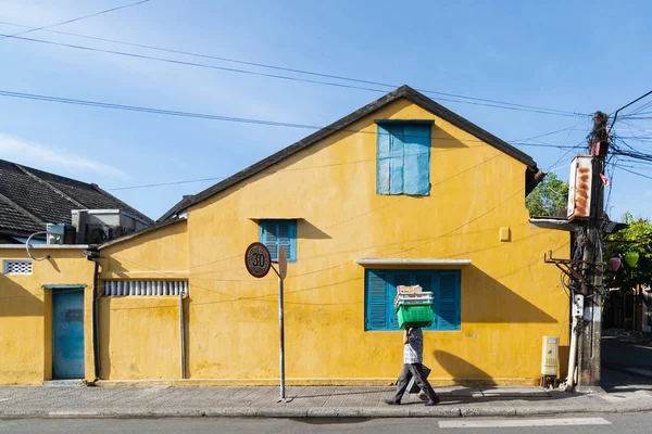 Hoi An, Vietnam - June 2019: street vendor walking by colorful house in old town — Stock Photo, Image