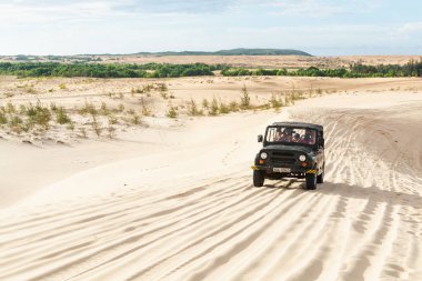 Mui Ne, Vietnam - Haziran 2019: gün doğumunda çöl kumtepelerinde giden off-road vintage sovyet arabası