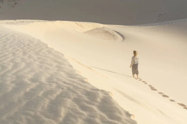 Female silhouette walking in desert sand dunes of Mui Ne, Vietnam