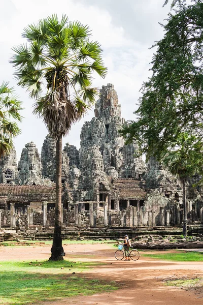 Jovem mulher andando de bicicleta ao lado do templo Bayon no complexo Angkor Wat, Camboja — Fotografia de Stock