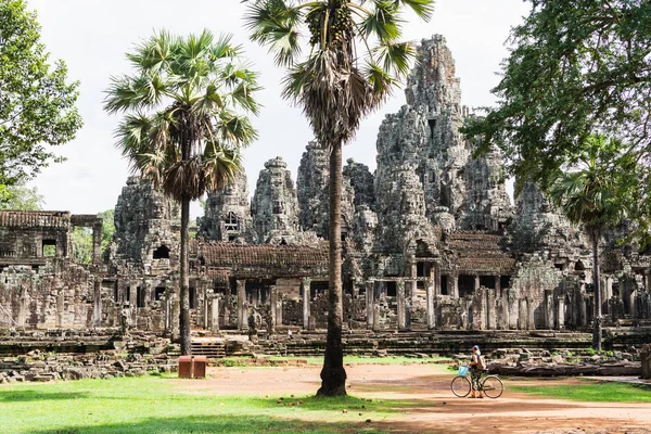 Young woman riding bicycle next to Bayon temple in Angkor Wat complex, Cambodia — Stock Photo, Image