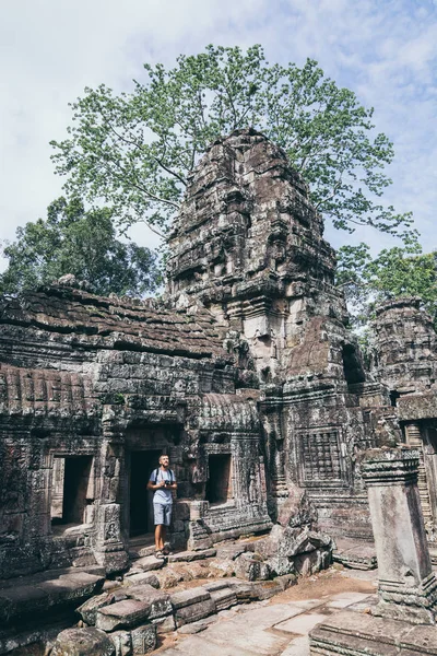 Homem caucasiano com câmera entre as ruínas do complexo do templo Angkor Wat em Siem Reap, Camboja — Fotografia de Stock