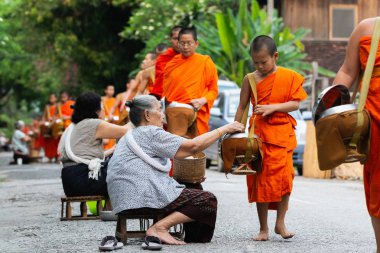 Luang Prabang, Laos - Mayıs 2019: Laoslular sadaka töreni sırasında Budist rahiplere adaklar yapıyor