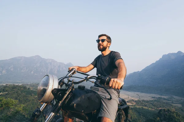 Kaukasischer junger Mann fährt Motorrad auf dem Gipfel der Berge in Vang Veng, Laos — Stockfoto
