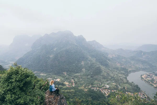 Junge kaukasische Frau auf dem Gipfel des Berges mit Blick auf das Flusstal im Dorf Nong Khiaw, Laos — Stockfoto