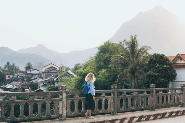 Blonde Kaukasische vrouw wandelen op de brug bij zonsondergang in Nong Khiaw, Laos — Stockfoto