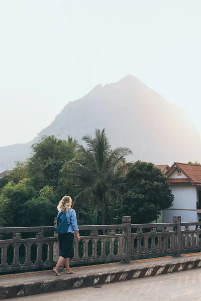 Blonde Kaukasische vrouw wandelen op de brug bij zonsondergang in Nong Khiaw, Laos — Stockfoto