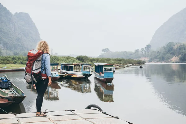 Femme blonde caucasienne avec sac à dos se tient sur la jetée du bateau dans le village de Muang Ngoi, Laos — Photo