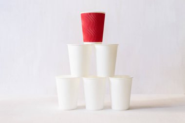 Kırmızı kağıt bardak beyaz kağıt bardakların üzerinde duruyor.