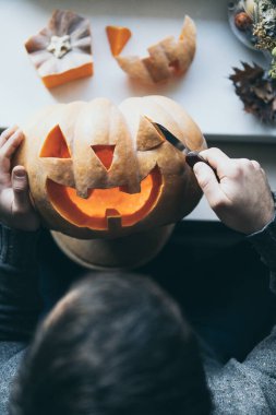 Cadılar Bayramı partisi için balkabağını bıçakla kesen adam.