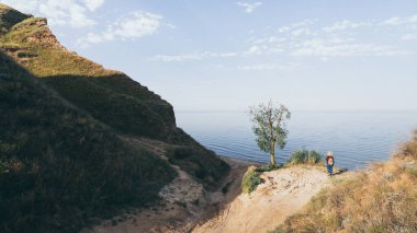 Güneşin doğuşunda denize bakan sırt çantalı yalnız gezgin kız. Kumsalda dikiliyorum