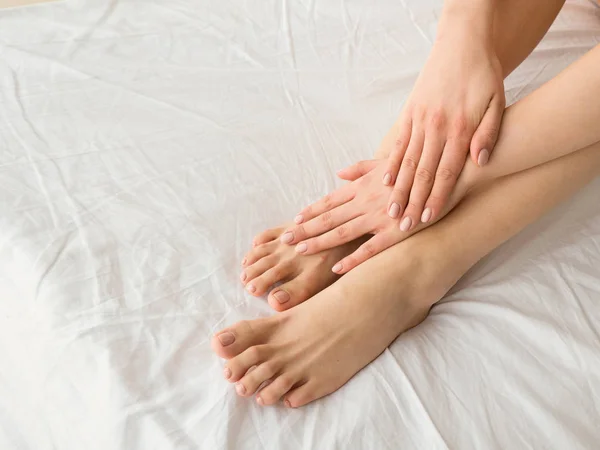 Мягкие женские ноги и руки на мягком и удобном постельном белье — стоковое фото