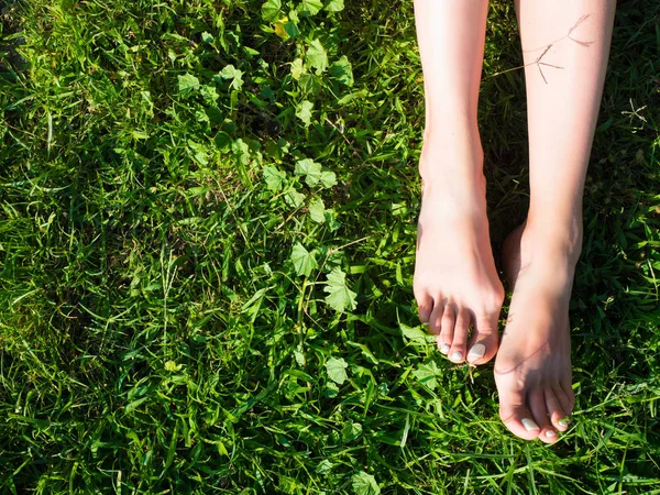 Feche as pernas cruzadas femininas andando na grama em um parque . — Fotografia de Stock