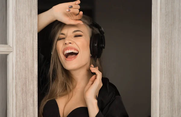 Retrato jovem com fones de ouvido cantando e ouvindo música em casa. Ela usa em lingerie preta ang vestido de vestir de seda . — Fotografia de Stock
