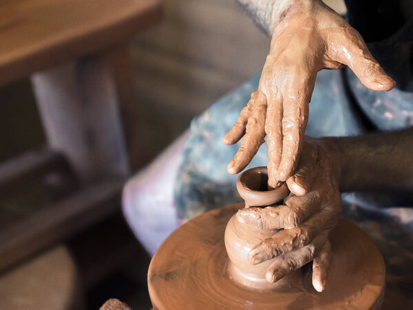 Professional male potter making ceramics on potters wheel in workshop, studio. Close up shot of potters hands. Handmade, art and handicraft concept.