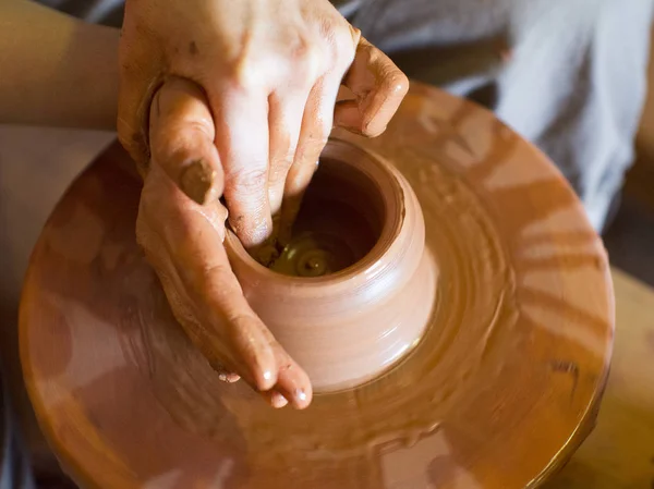 Rotating potters wheel and clay ware on it vase : taken from above. Hands in clay. Pottery: male ceramist creates a hand made clay product. Process of rotation of potters wheel, hands of ceramist.