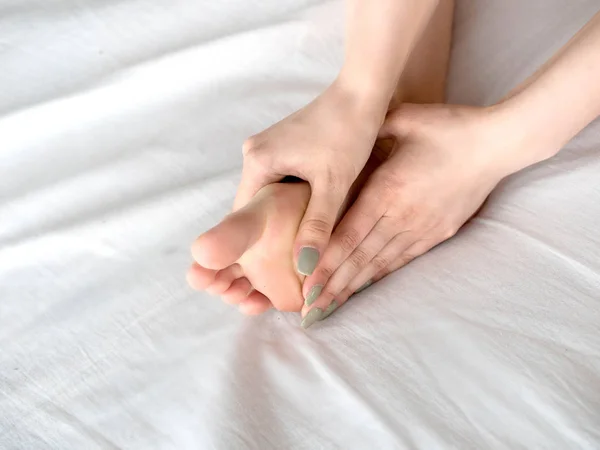 Young woman touching her leg on bed — Stock Photo, Image