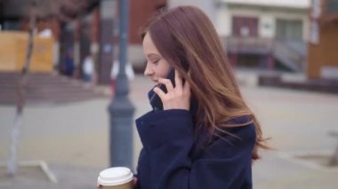 İş kadını kullanma Smartphone kentin çekici esmer. Güzel genç iş kadını konuşarak telefon ve içme kahve