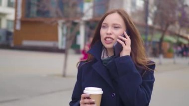 İş kadını kullanma Smartphone kentin çekici esmer. Güzel genç iş kadını konuşarak telefon ve içme kahve