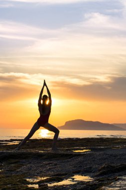 Gün batımında denizde meditasyon yapan kız. Yoga silueti. Fitness ve sağlıklı yaşam tarzı.