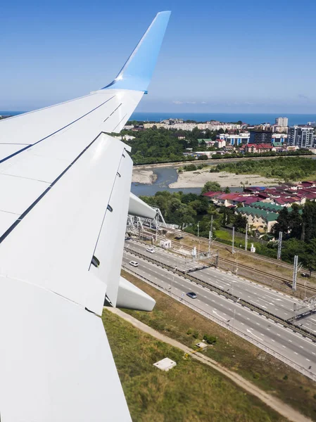 Вид через иллюминатор самолета с культивируемыми полями, голубым небом, легкими облаками и частью крыла самолета — стоковое фото