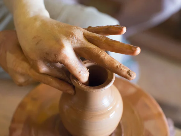 Rotating potters wheel and clay ware on it vase: taken from above. Hands in clay. Pottery: male ceramist creates a hand made clay product. Process of rotation of potters wheel, hands of ceramist — Stock Photo, Image