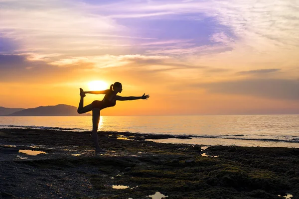 Joven practicando yoga en la playa durante el atardecer — Foto de Stock