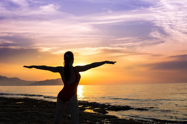 Jeune fille pratiquant le yoga sur la plage pendant le coucher du soleil — Photo