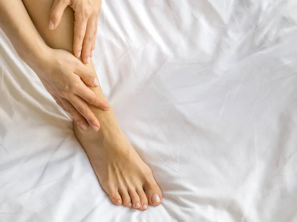 Młoda kobieta masuje jej stopy na łóżku., pojęcie opieki zdrowotnej. — Zdjęcie stockowe