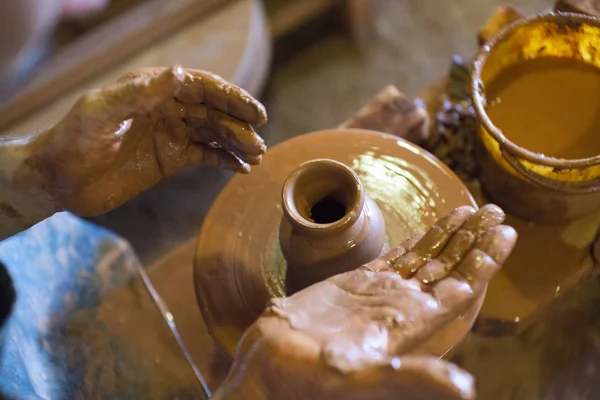 Otáčení kola a hliněné nádobí na něm keramiky váza: převzaty z výše. Ruce do hlíny. Keramika: mužské keramik vytváří ručně vyráběné hliněné produktu. Proces otáčení hrnčíři kola, ruce keramik. — Stock fotografie