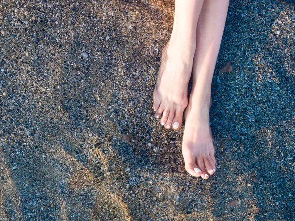 Két pár női és egy pár férfi láb egy sárga homokos strand felülnézet. — Stock Fotó