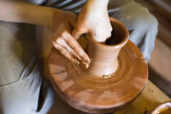 Rotating potters wheel and clay ware on it vase : taken from above. Hands in clay. Pottery: male ceramist creates a hand made clay product. Process of rotation of potters wheel, hands of ceramist. — Stock Photo, Image