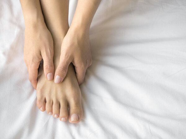 Young woman massaging her foot on the bed., Healthcare concept.