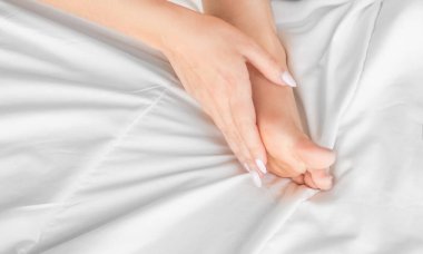 İnce, mükemmel ve güzel kadın bacak yatakta bacak. Erotik yatakta yatarken görüntü kırpılmış güzel kadın yatak odasında. Buruşuk beyaz yatak örtüsü. Yatay fotoğraf, üstten görünüm