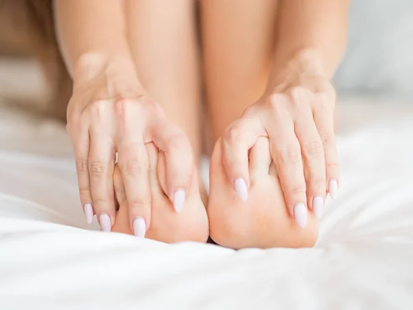 Kobiece nogi na łóżku pokryte arkuszy — Zdjęcie stockowe
