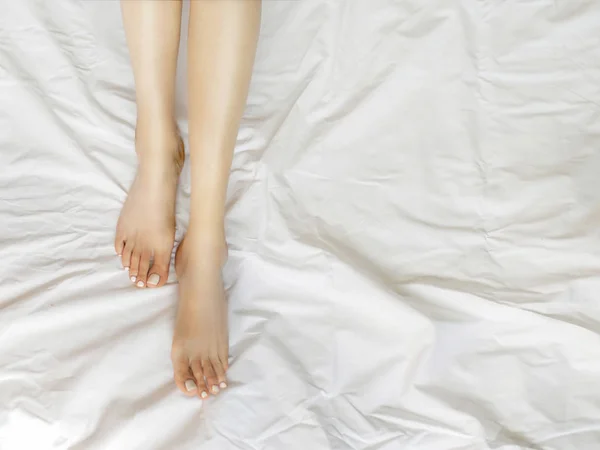 Woman legs in white bed sheets — Stock Photo, Image