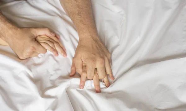 couple hands pulling white sheets in ecstasy, orgasm. Concept of passion. Orgasm. Erotic moments. Intimate concept. Sex couple. Bedroom.