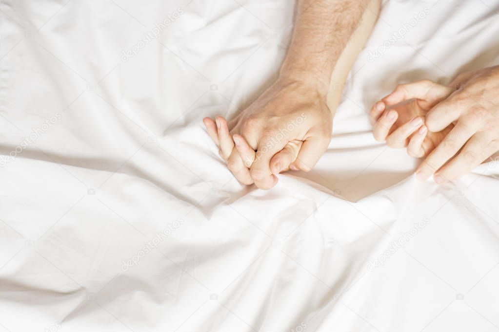 couple hands pulling white sheets in ecstasy, orgasm. Concept of passion. Orgasm. Erotic moments. Intimate concept. Sex couple. Bedroom.