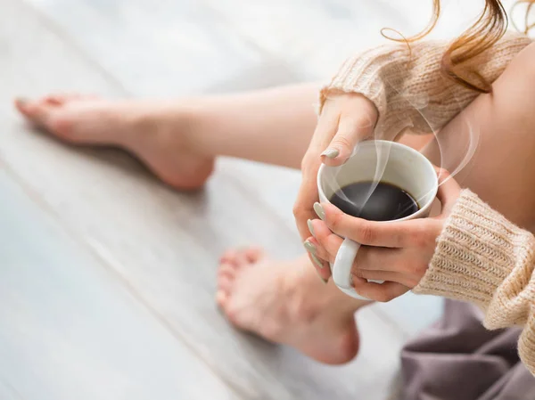 Foto de piernas y manos femeninas relajándose y bebiendo café en la cama . — Foto de Stock