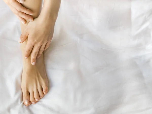 Женщина наносит крем на ноги, крупным планом — стоковое фото