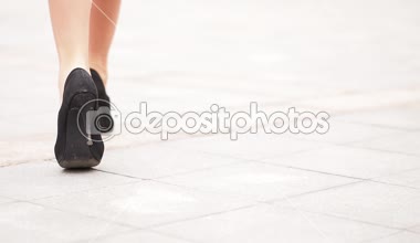 Yüksek topuklu ayakkabılı kadın bacakları şehir caddesinde yürüyor. Şehirdeki yüksek topuklu ayakkabılı genç iş kadınının ayakları. İşe giden bir kız. Yavaş çekim. Yakın çekim.