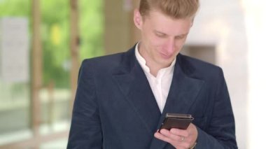 - Telefon. İş adamı, şehrin iş bölgesindeki akıllı telefonlarda uygulamayla mesajlaşma kullanıyor. Genç işadamı cep telefonunu açık havada takım elbiseli mutlu bir şekilde kullanıyor. Kentsel erkek profesyonel.