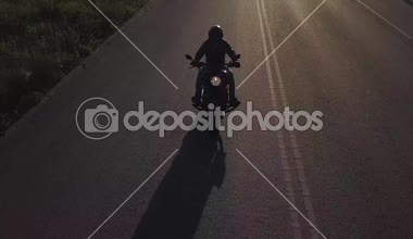bir adam bir motosiklet ile yolda gidiyor. Kamera geri binici eşlik taşınır. Uçak video.