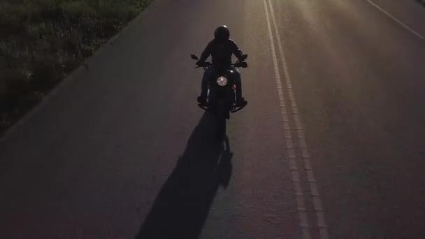 Muž na motorce jezdí na silnici. Kamera se pohybuje zpět doprovázet jezdce. Video z dron.