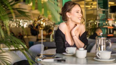 Genç kadın bir Cafe açık havada çay içme. Yaz şehir arka plan. Sığ derinlik-in tarla. Tonda fotoğraf.