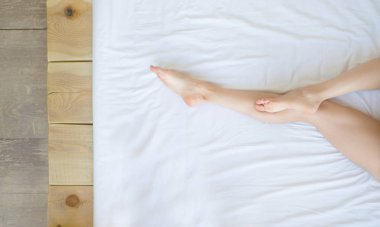 Tatlı kadın bacaklar beyaz üzerinde uyku ile yatak, güzellik ve cilt bakım kavramı.