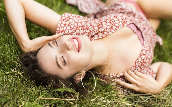 Güzel kız Field.Green çim üzerinde yalan. Mutlu ve gülümseyerek