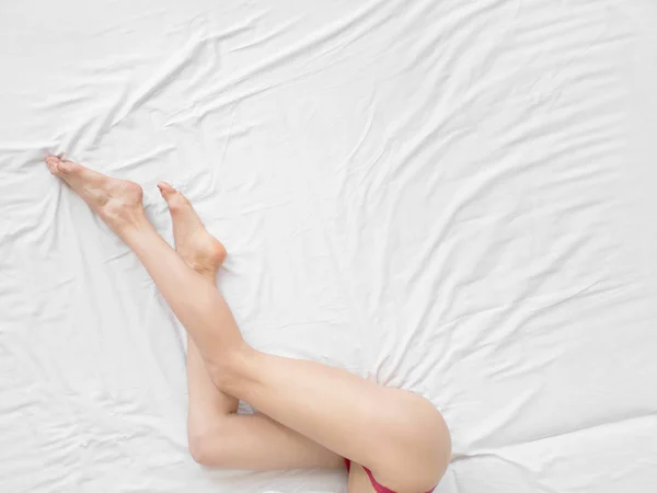 Ноги женщины крупным планом со сном на белой кровати, красота и уход за кожей . — стоковое фото