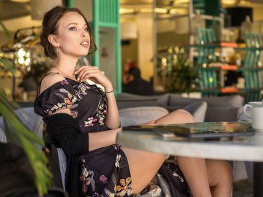 Genç kadın bir Cafe açık havada çay içme. Yaz şehir arka plan. Tonda fotoğraf.