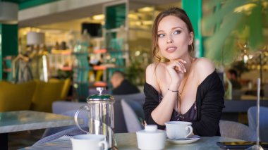 Genç kadın bir Cafe açık havada çay içme. Yaz şehir arka plan. Tonda fotoğraf.
